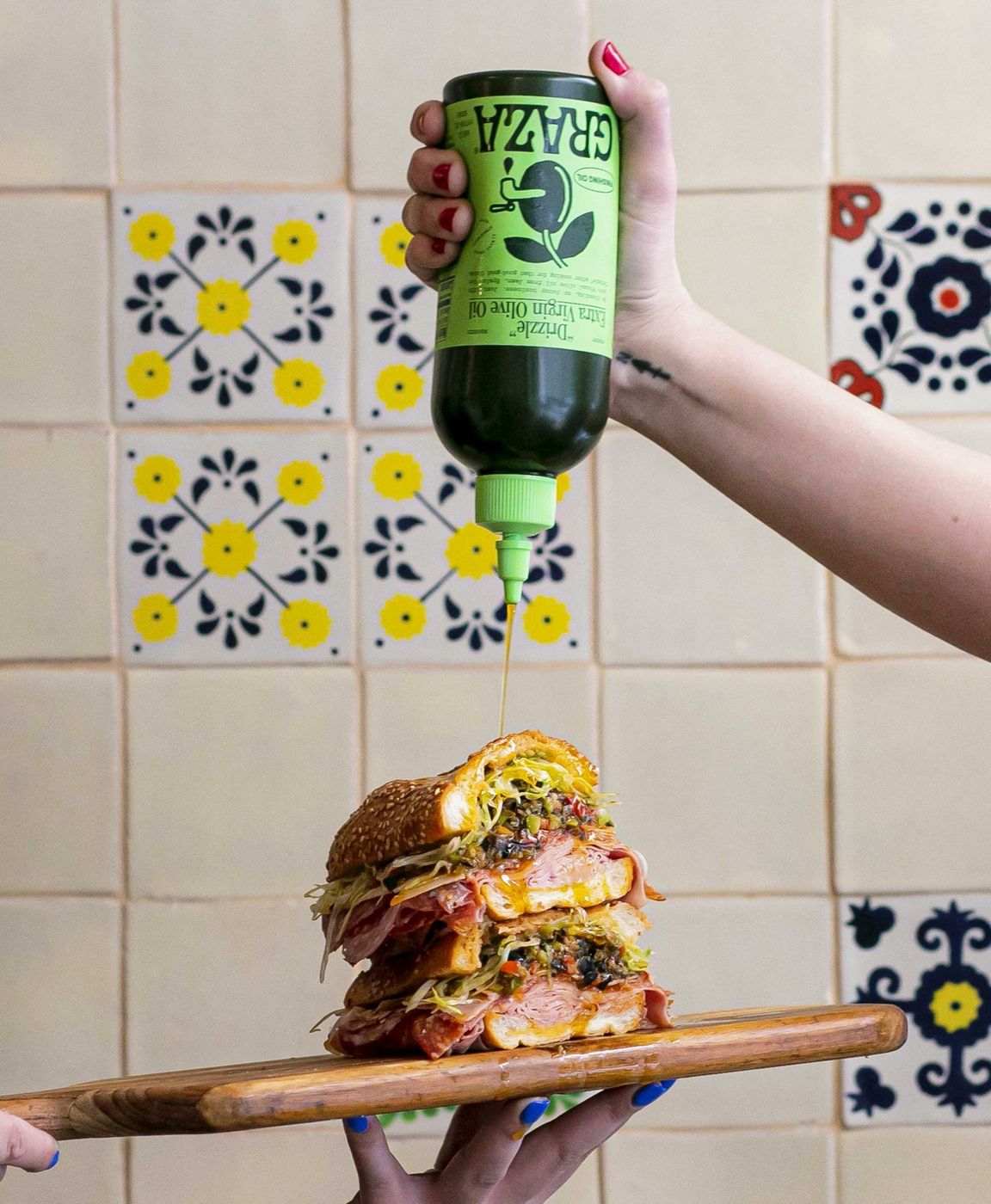 A hand squeezing “Drizzle” over a sandwich